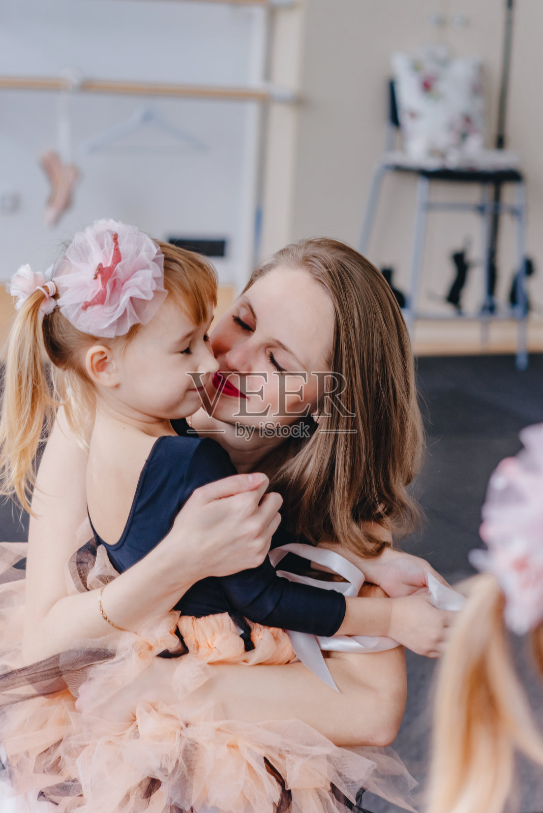 一个小女孩和她的妈妈拥抱在一起。照片摄影图片