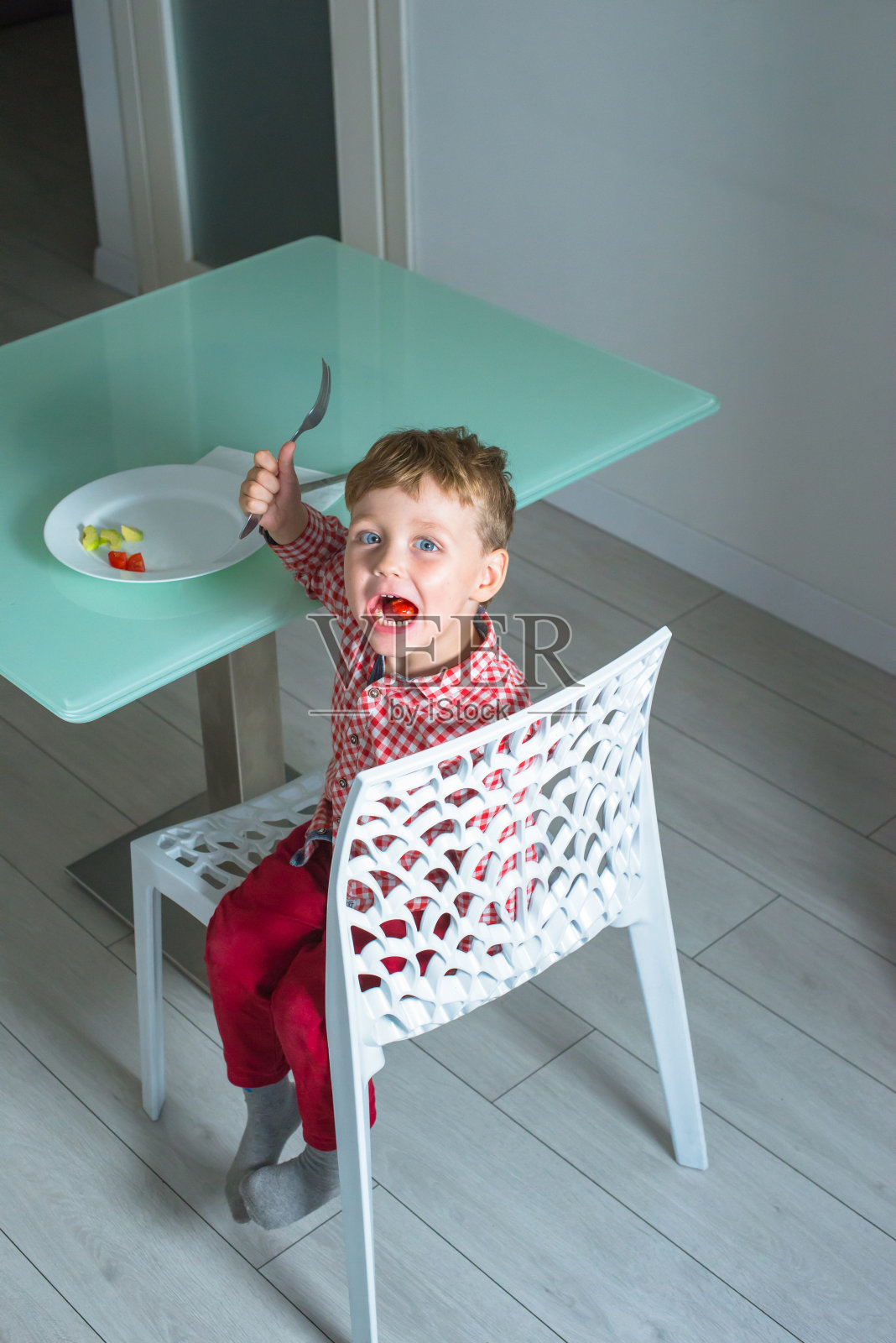 男孩坐在椅子上吃健康的食物。照片摄影图片