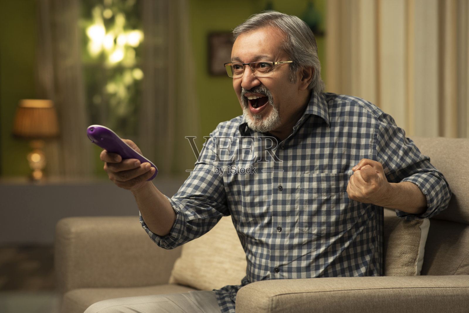 一个成熟的男人坐在沙发上看电视-库存照片照片摄影图片