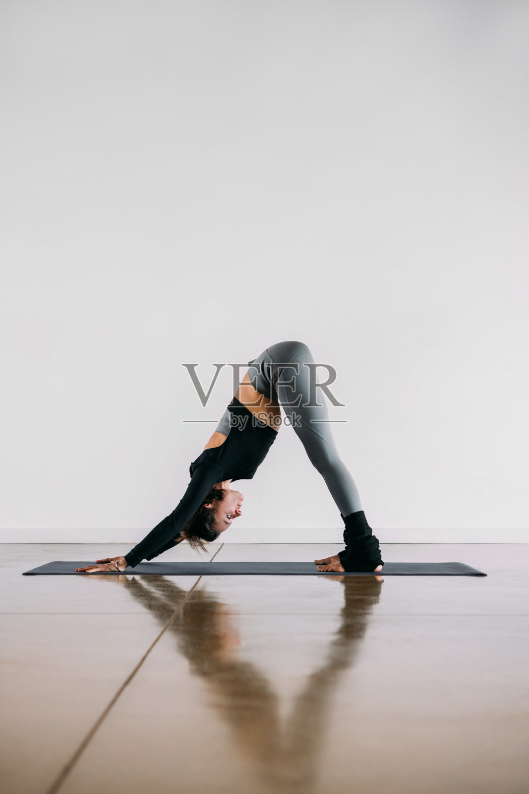 面对狗瑜伽姿势-女教练在运动服装进行锻炼。照片摄影图片