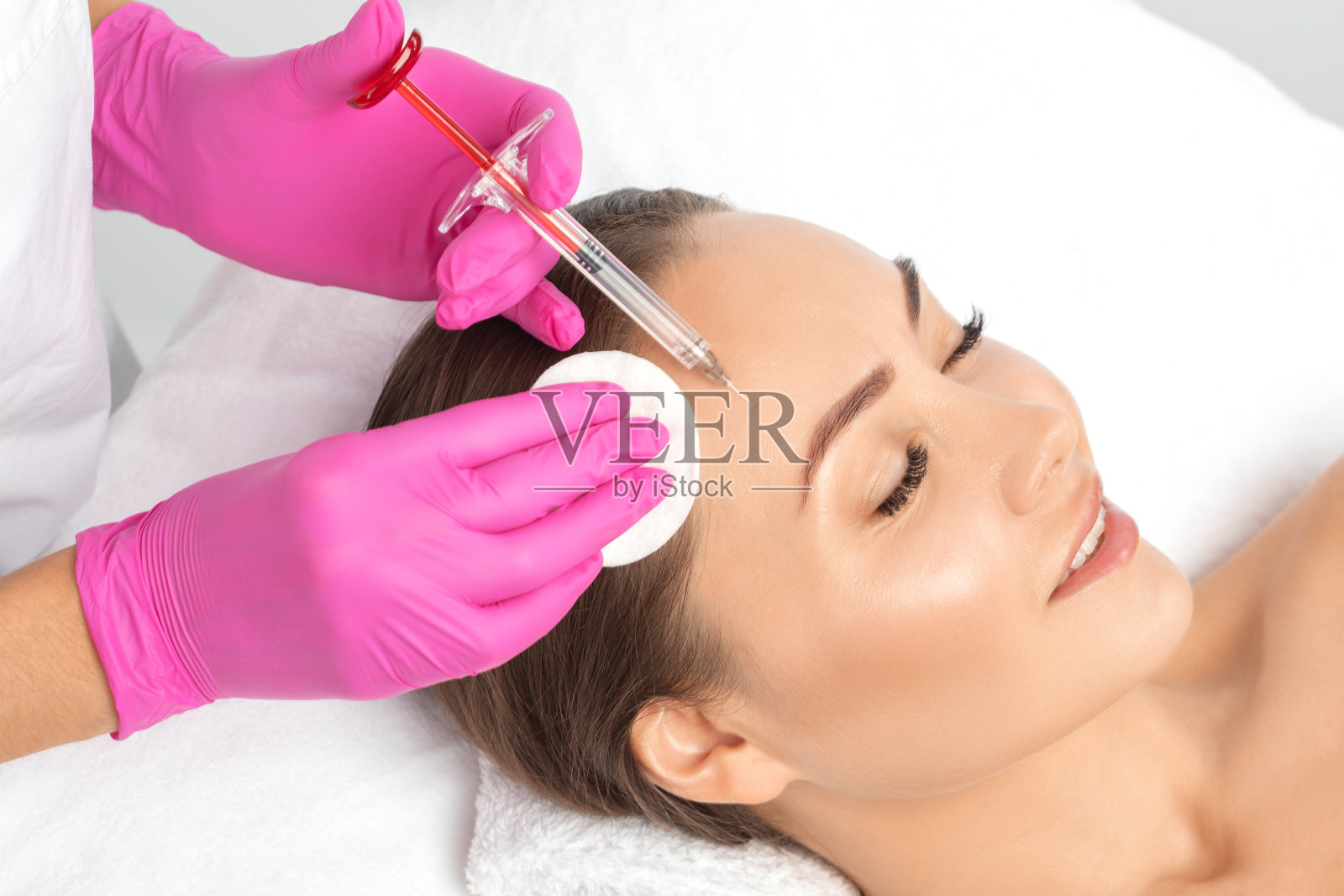 美容师使年轻化抗皱注射在一个美丽的女人的脸上。在美容院做女性美容。照片摄影图片