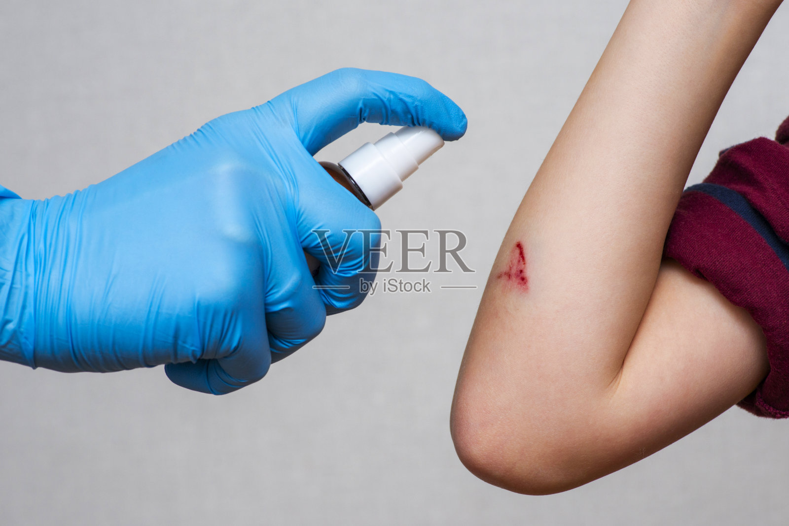 医生用手向孩子手上的伤口喷一种防腐剂。治疗伤口。急救。照片摄影图片