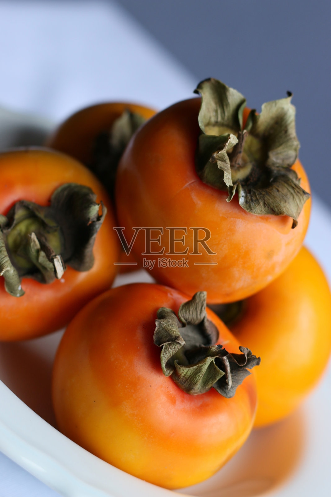 新鲜成熟的柿子在白色经典设计盘子,天堂棕榈树照片摄影图片