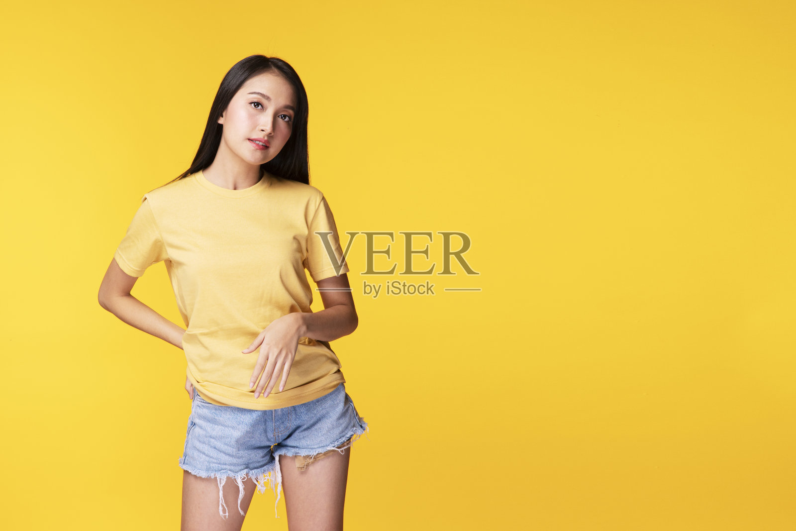 生活方式放松的概念。积极微笑的亚洲女性穿着休闲服装,双臂交叉站在孤立的黄色背景。照片摄影图片