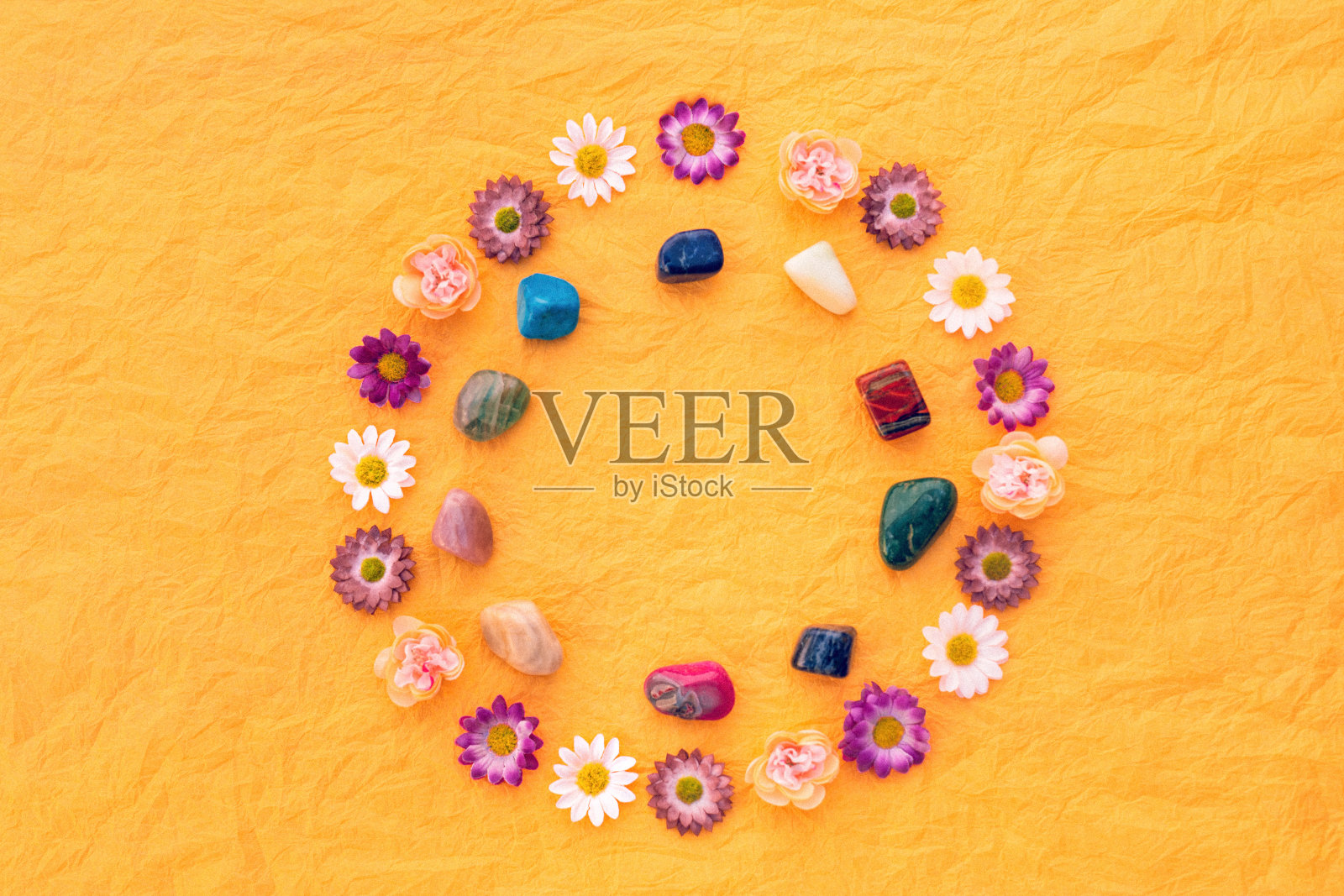 以黄色皱巴巴的纸巾为背景的冥想或治疗石头的曼陀罗照片摄影图片