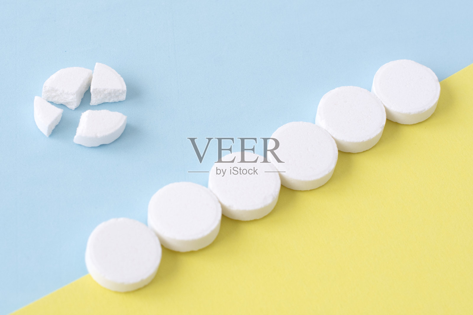蓝色和黄色背景上的白色圆形药丸。健康的概念照片摄影图片