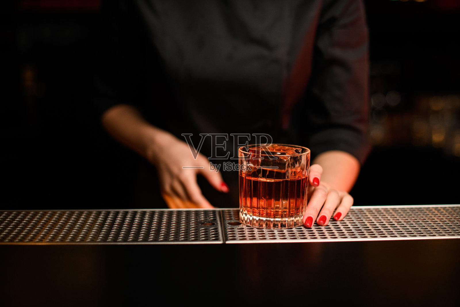 老式的杯子上的饮料柜台和一个女酒保的手拿着它照片摄影图片