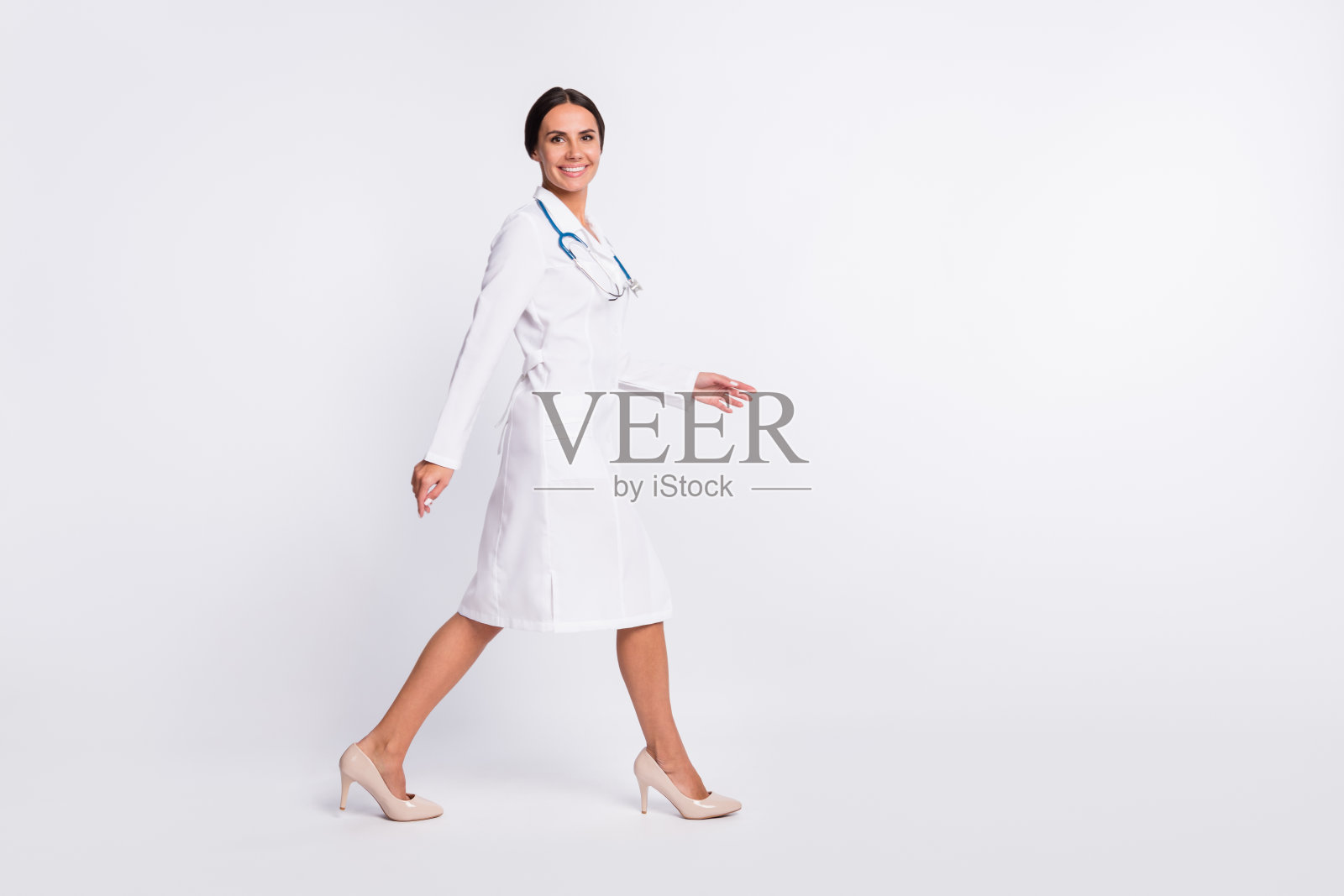 全身照片的自信可爱的年轻女子治疗师穿着正式的外套行走的空间孤立的白色背景照片摄影图片