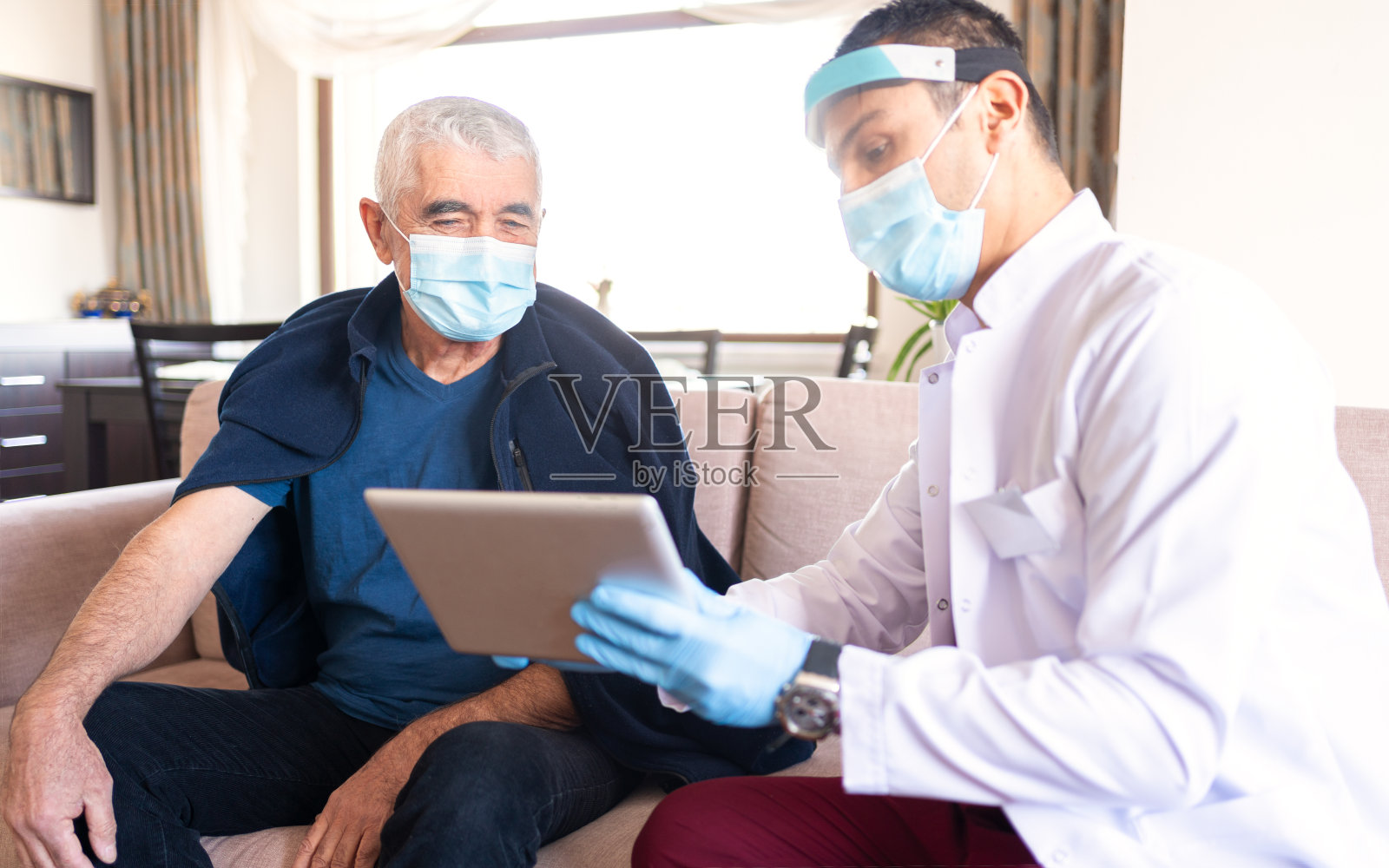 男医生在家用平板电脑向老年病人讲解测试结果。照片摄影图片