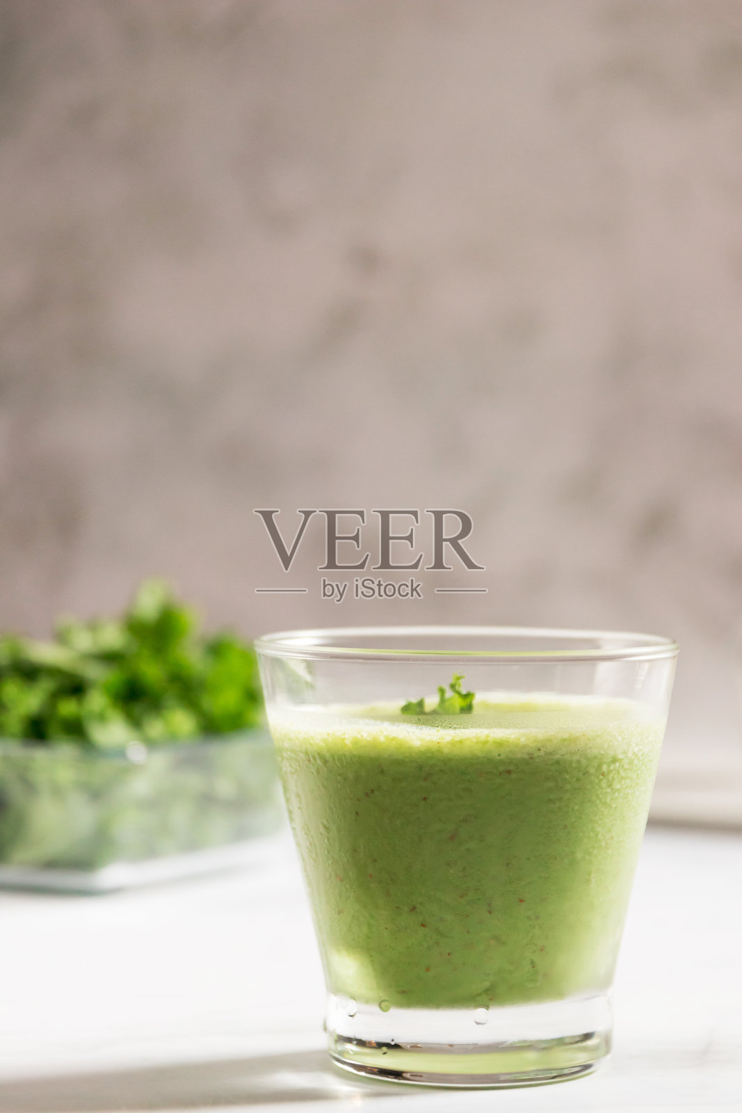 健康的绿色羽衣甘蓝奶昔和希腊酸奶在一个玻璃隔离在白色的桌子背景,俯视图。羽衣甘蓝被认为是一种超级食物,因为它富含维生素和矿物质。照片摄影图片