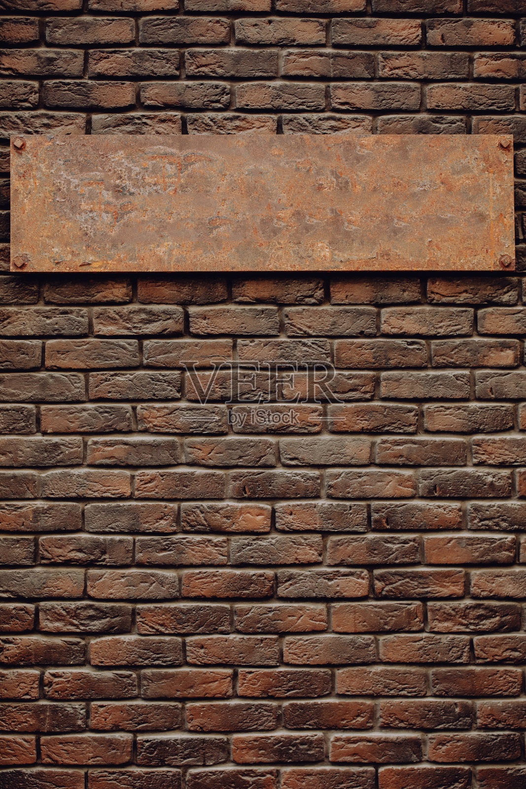 棕色砖墙上的旧空白金属标志。这个牌子看起来很贵。照片摄影图片