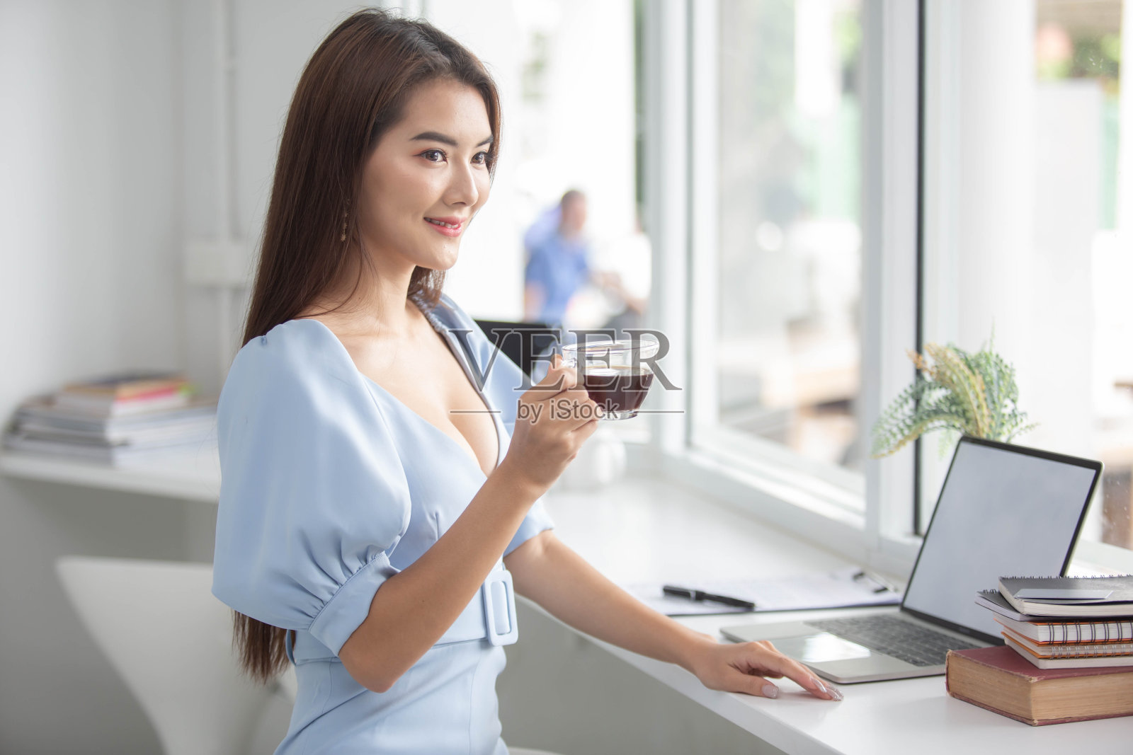 一个漂亮的女孩在办公室工作,有一台电脑,一个电话和一杯咖啡照片摄影图片