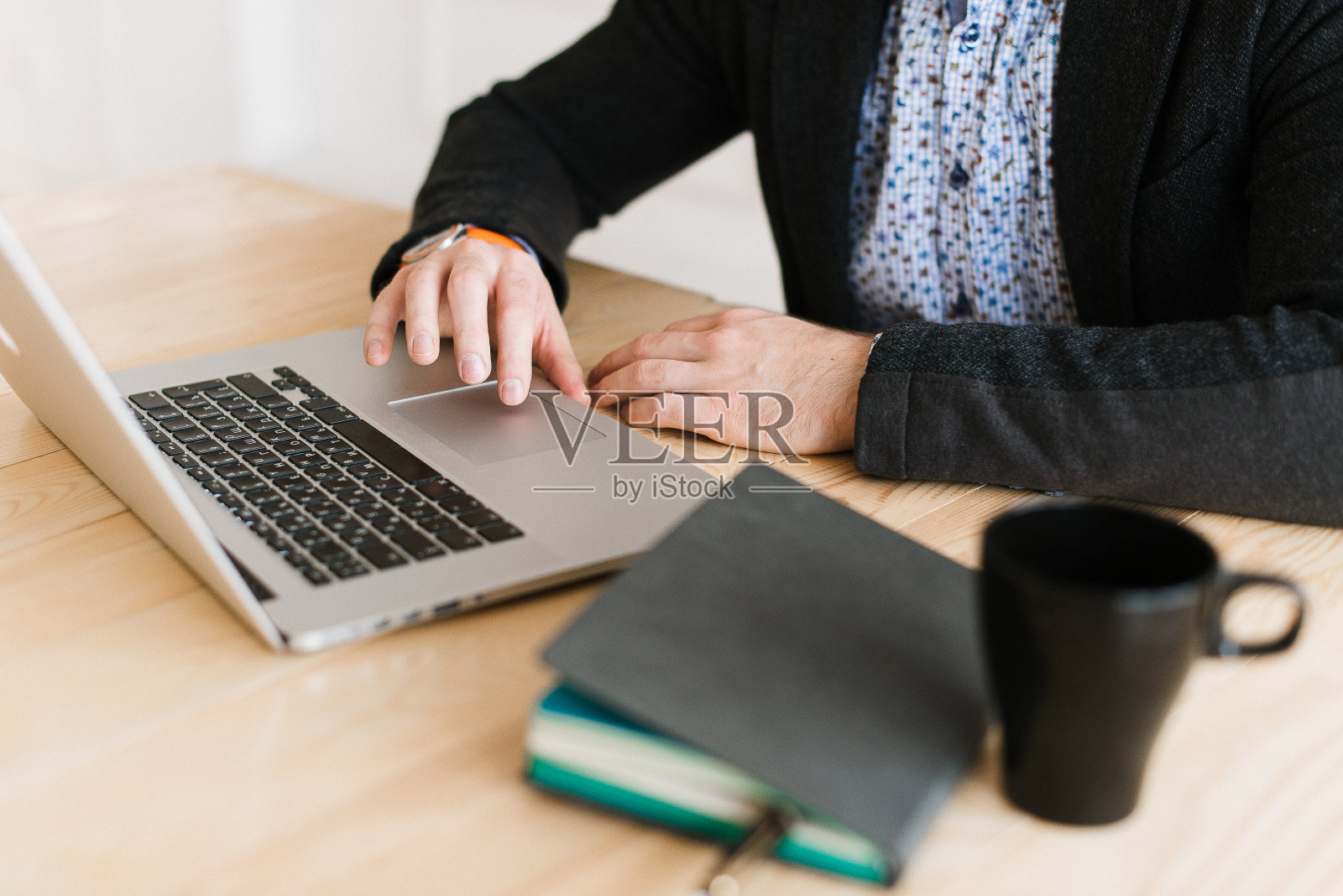 一个人坐在书桌前用笔记本电脑工作的特写。日记在桌子上。照片摄影图片