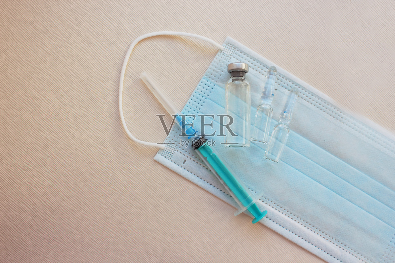 带针注射器,带药的护身符放在医用口罩上,背景光线较亮。接种疫苗。冠状病毒医学和免疫的概念。接种预防病毒感染的疫苗。断然。本空间照片摄影图片