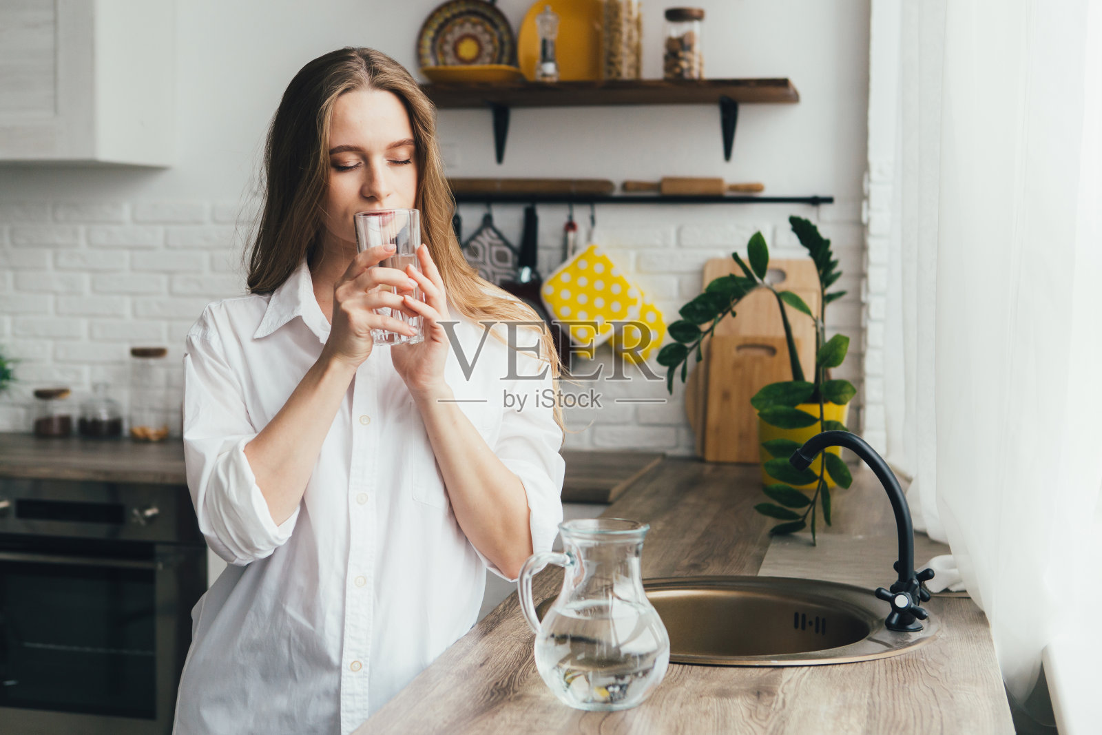 怀孕的女孩在厨房里喝干净的水照片摄影图片