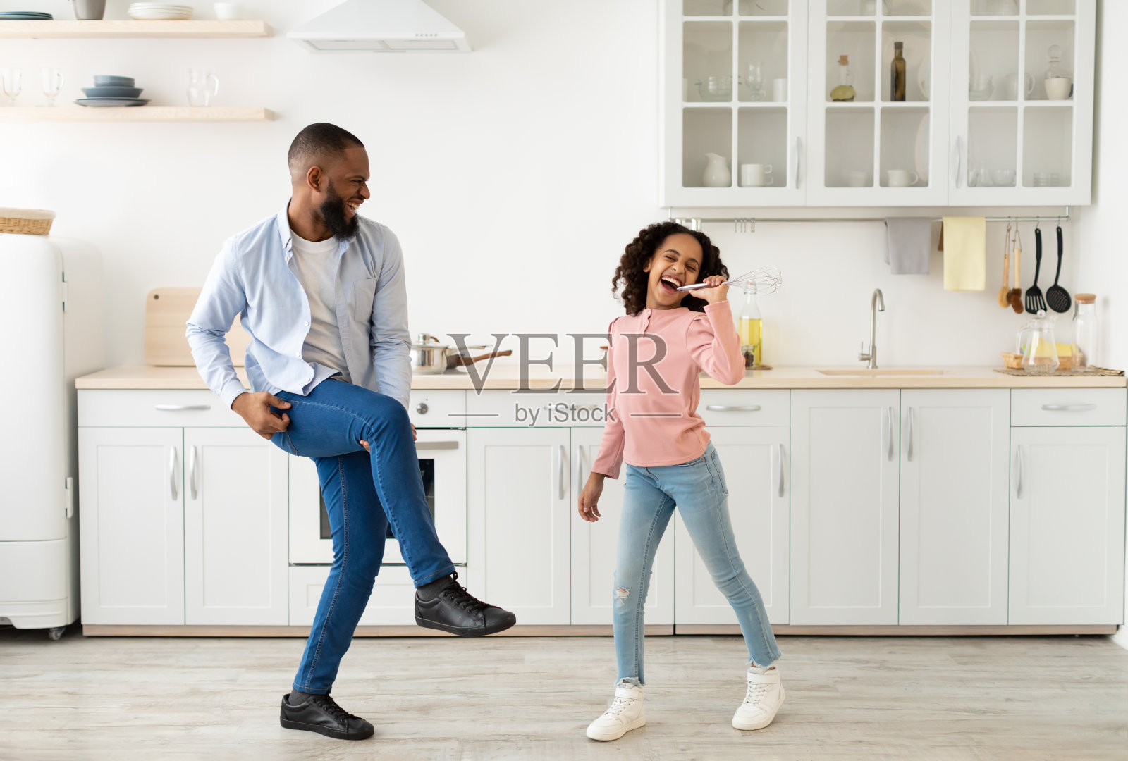 黑人爸爸和女儿边唱歌边跳舞边做饭照片摄影图片