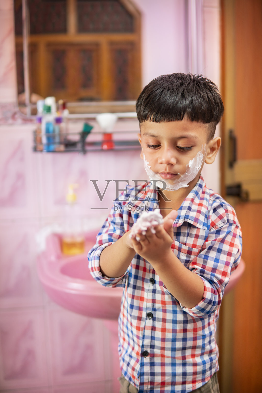 可爱的小男孩在浴室玩剃须泡沫。照片摄影图片