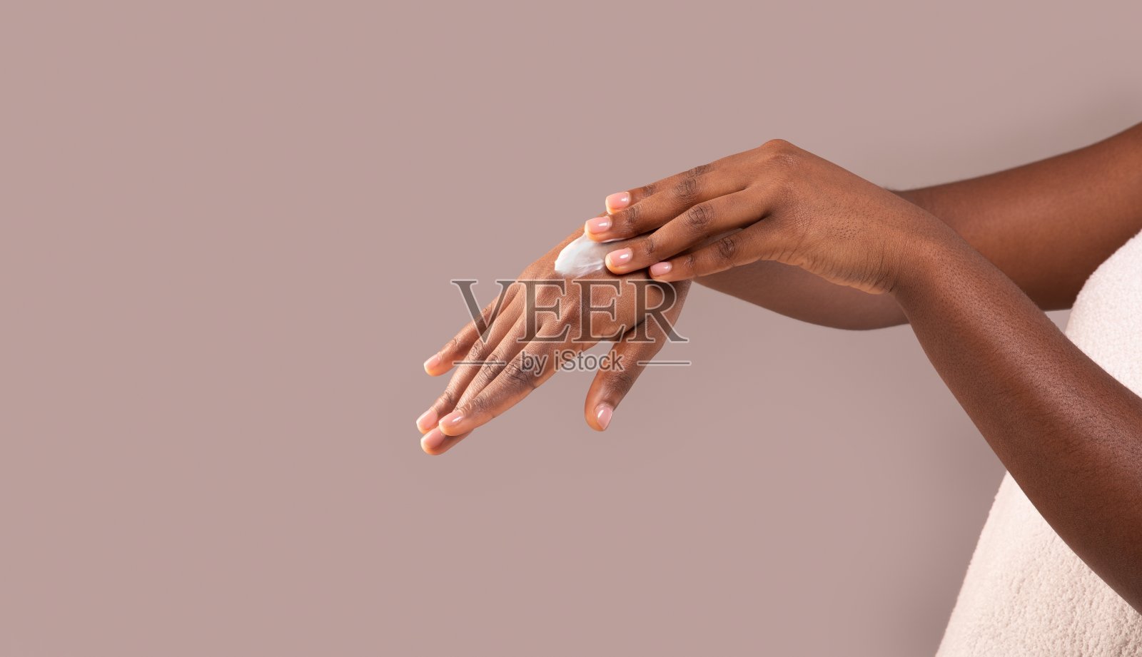 干性皮肤的治疗。非裔美国女性在手上涂抹保湿霜照片摄影图片