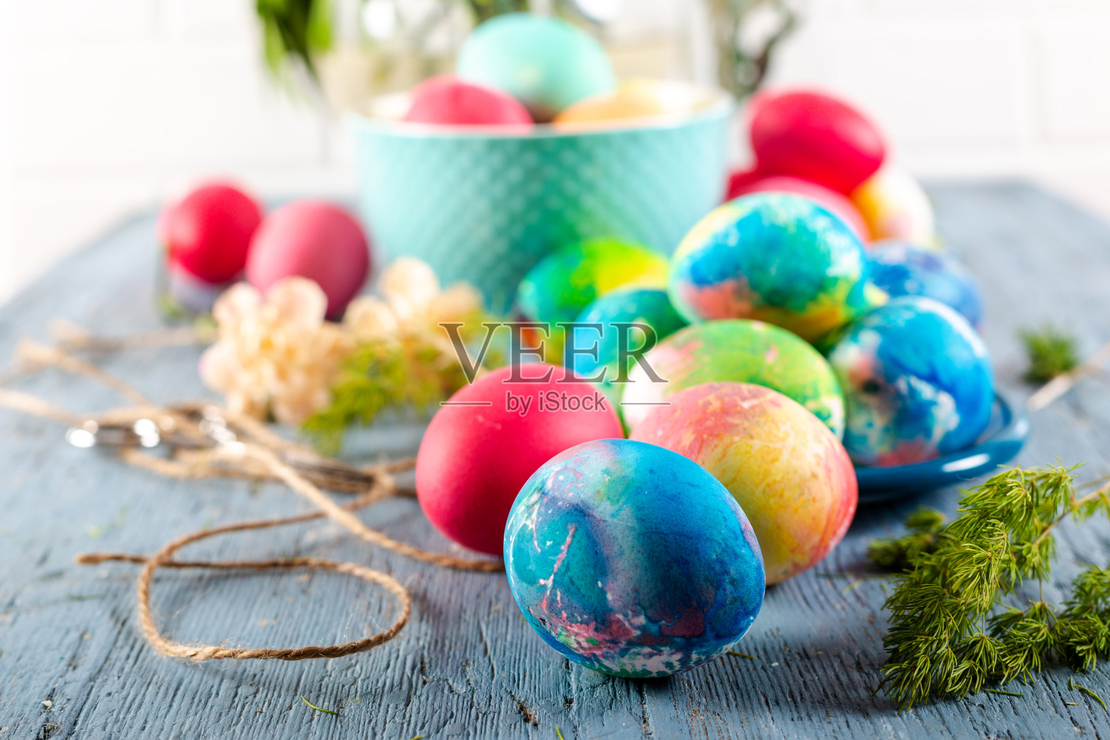 蓝色的木桌上放着五颜六色的复活节彩蛋。照片摄影图片