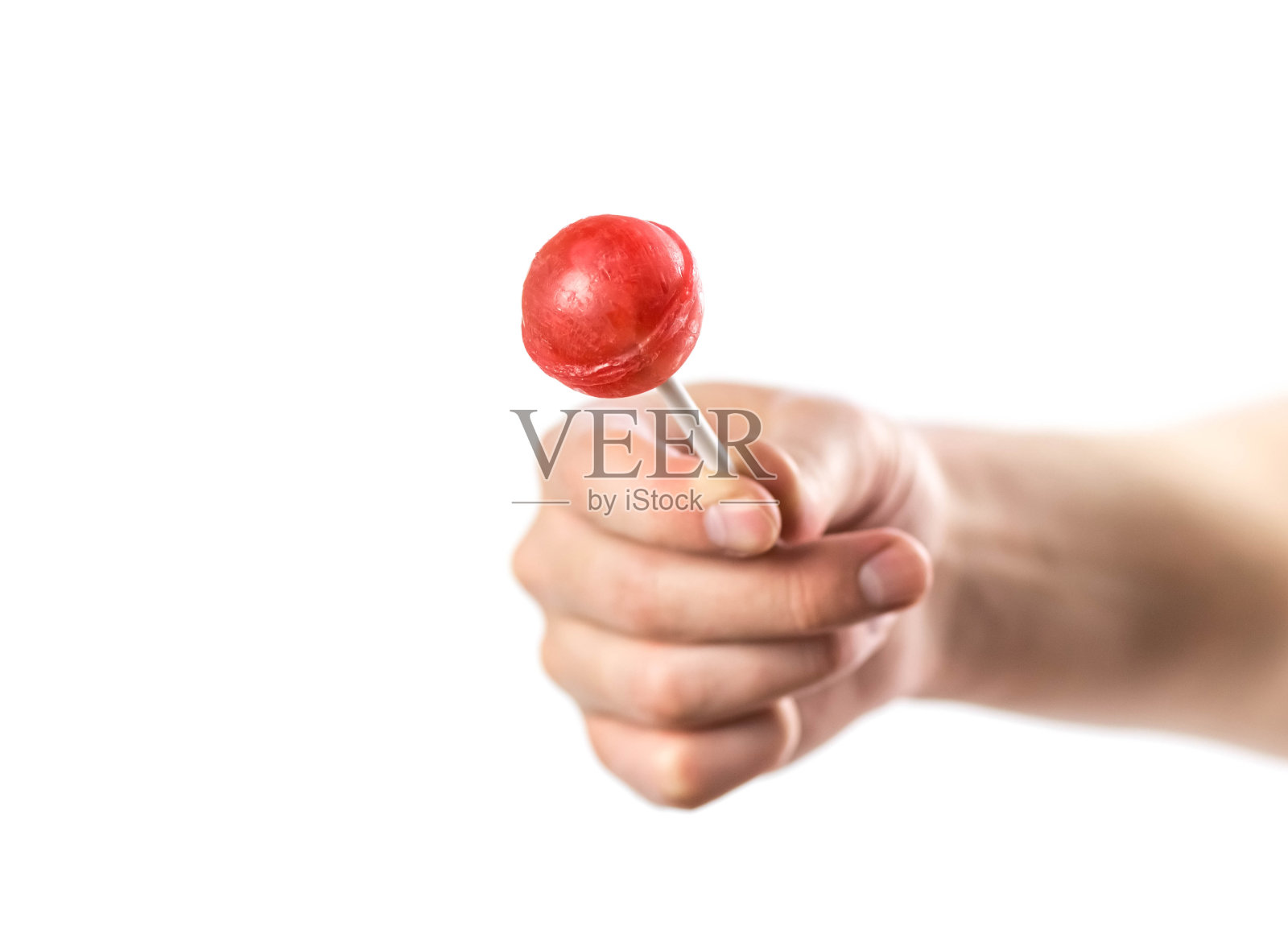 这只手拿着一根红色的棒棒糖。关闭了。孤立在白色背景上照片摄影图片