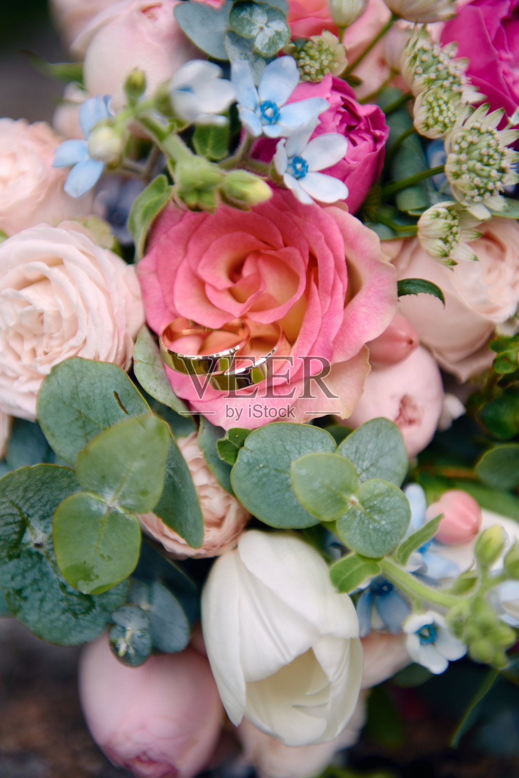 两个金色的结婚戒指上的婚礼花束的粉色和白色的玫瑰在户外,复制空间的特写。有选择性的热点。结婚的概念照片摄影图片