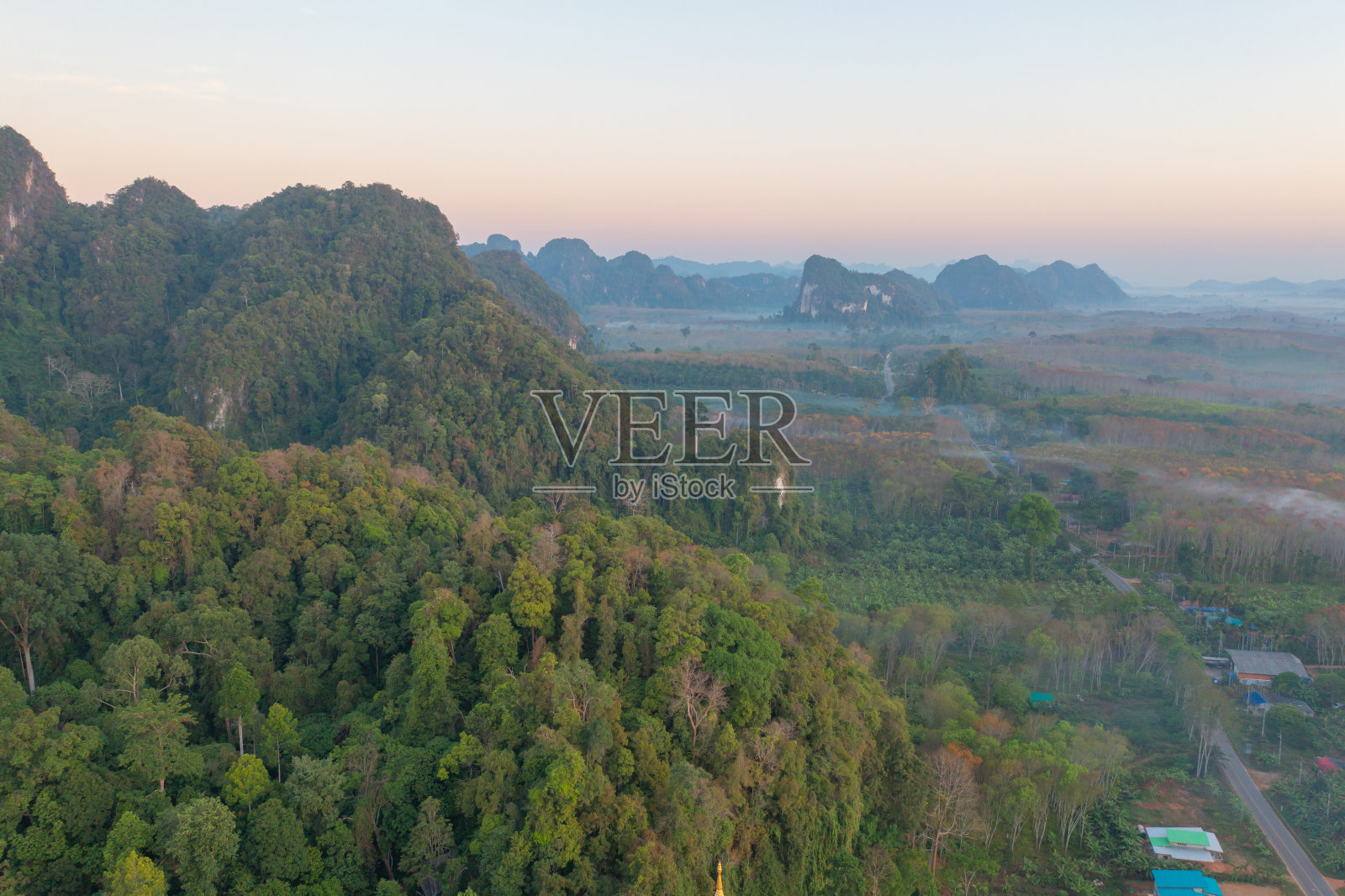 鸟瞰图的森林树木与雾雾和绿色的山山在日落。自然景观背景,泰国。照片摄影图片