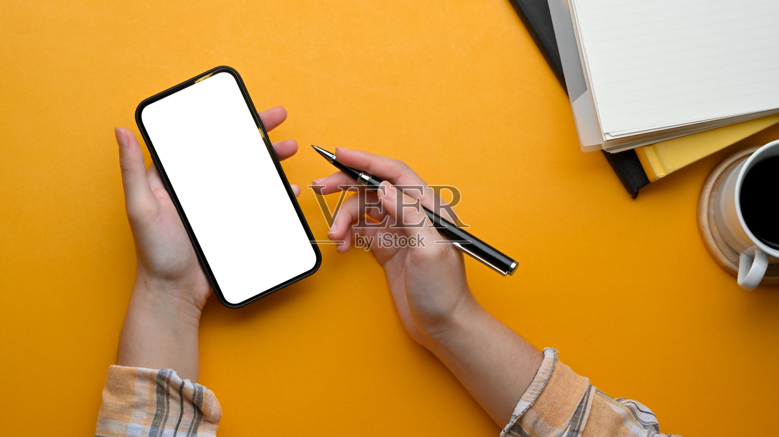 女性自由职业者,在时尚的工作空间里用智能手机工作,手里拿着笔照片摄影图片