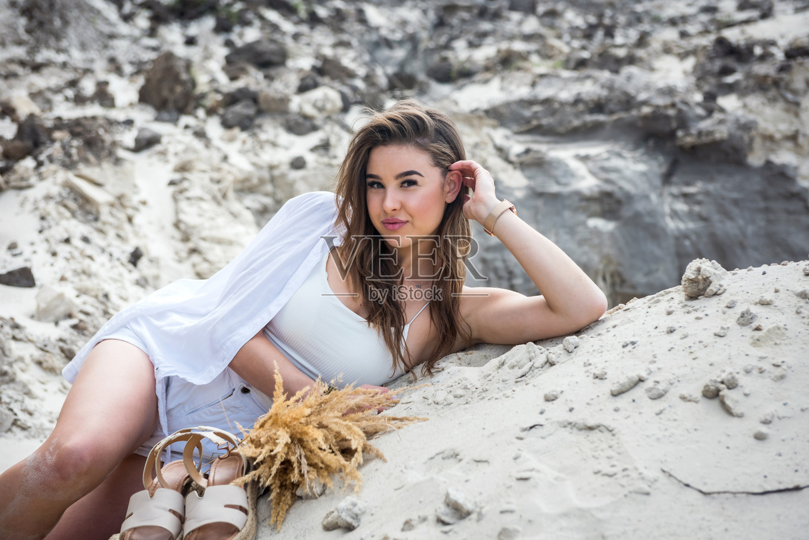 非常漂亮的小女孩躺在白色的沙滩上晒太阳照片摄影图片