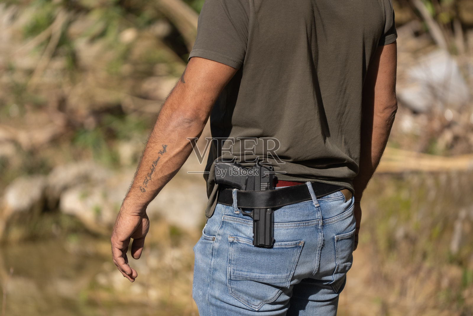 一个把枪塞进裤子里的男人。照片摄影图片