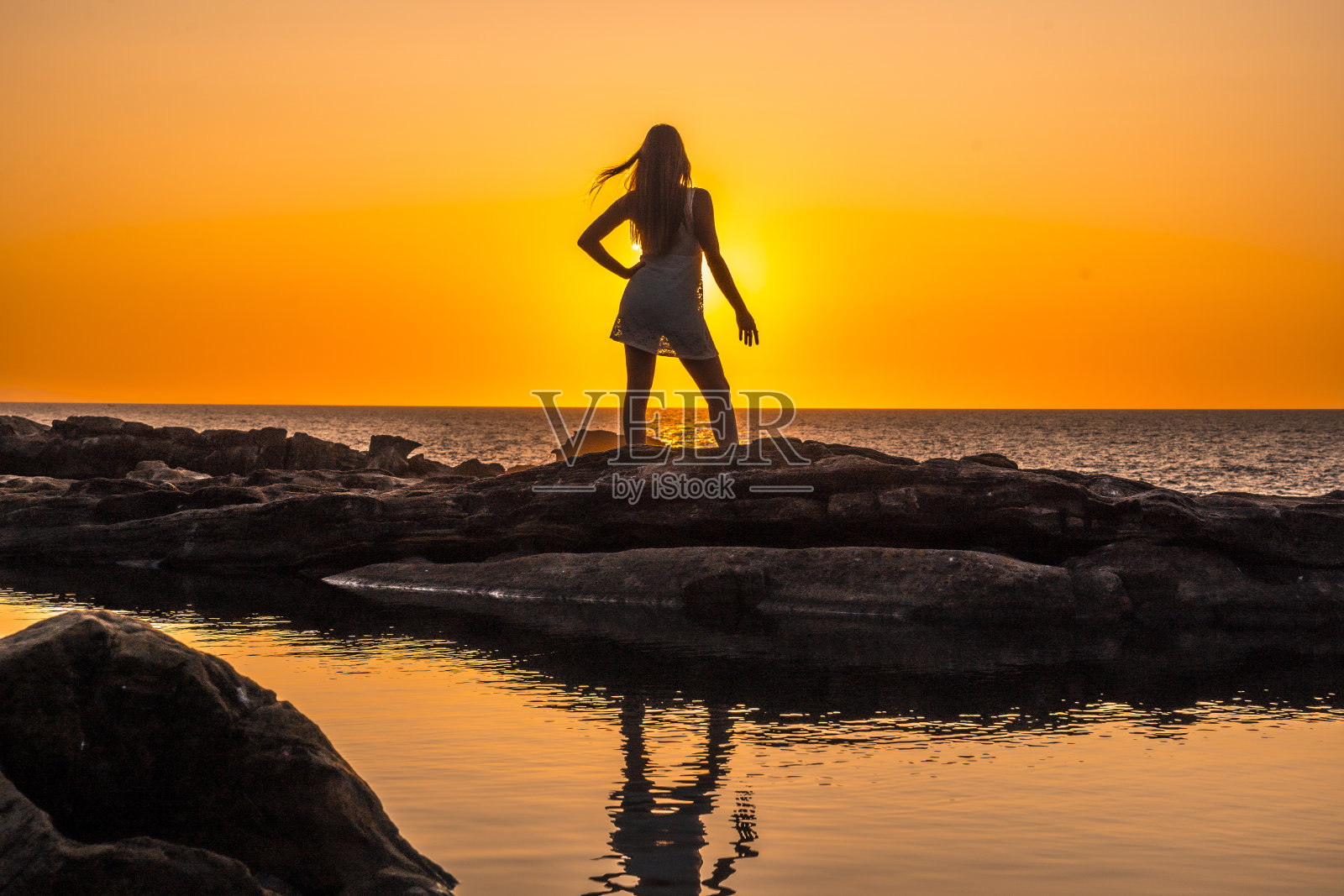 生活方式,一个年轻的金发女郎的剪影在一个橙色的日落白色的裙子照片摄影图片