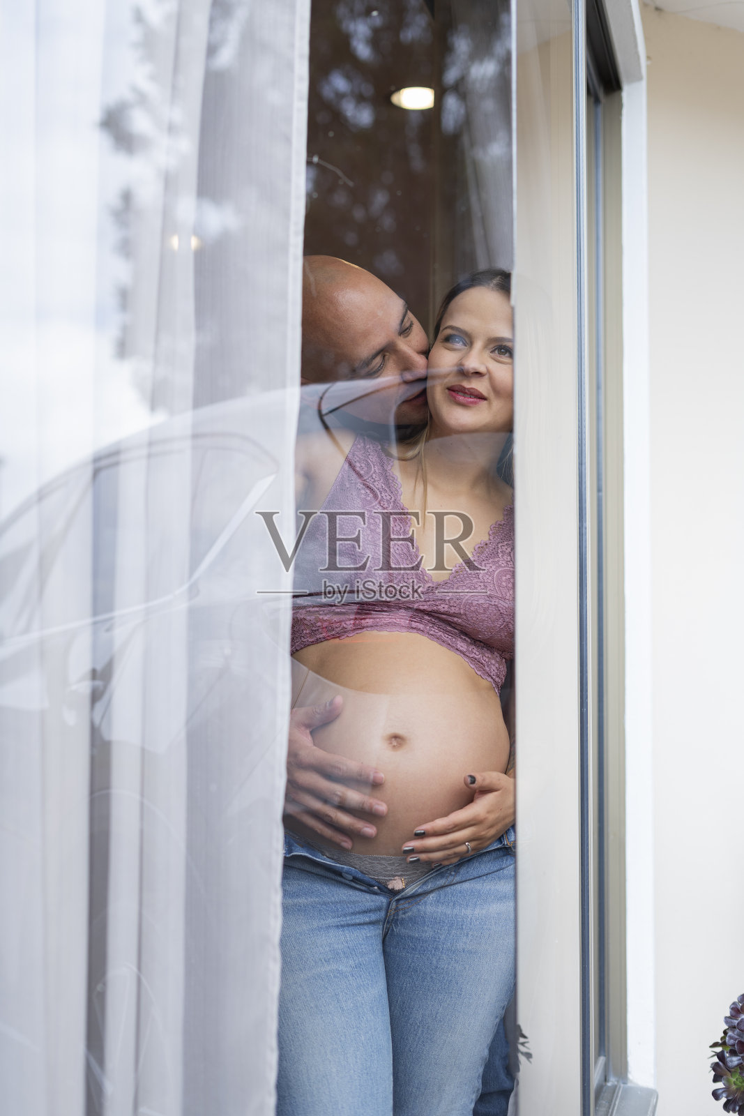 一对漂亮的父母一边看着窗外一边抚摸着自己的肚子一边看着窗外照片摄影图片