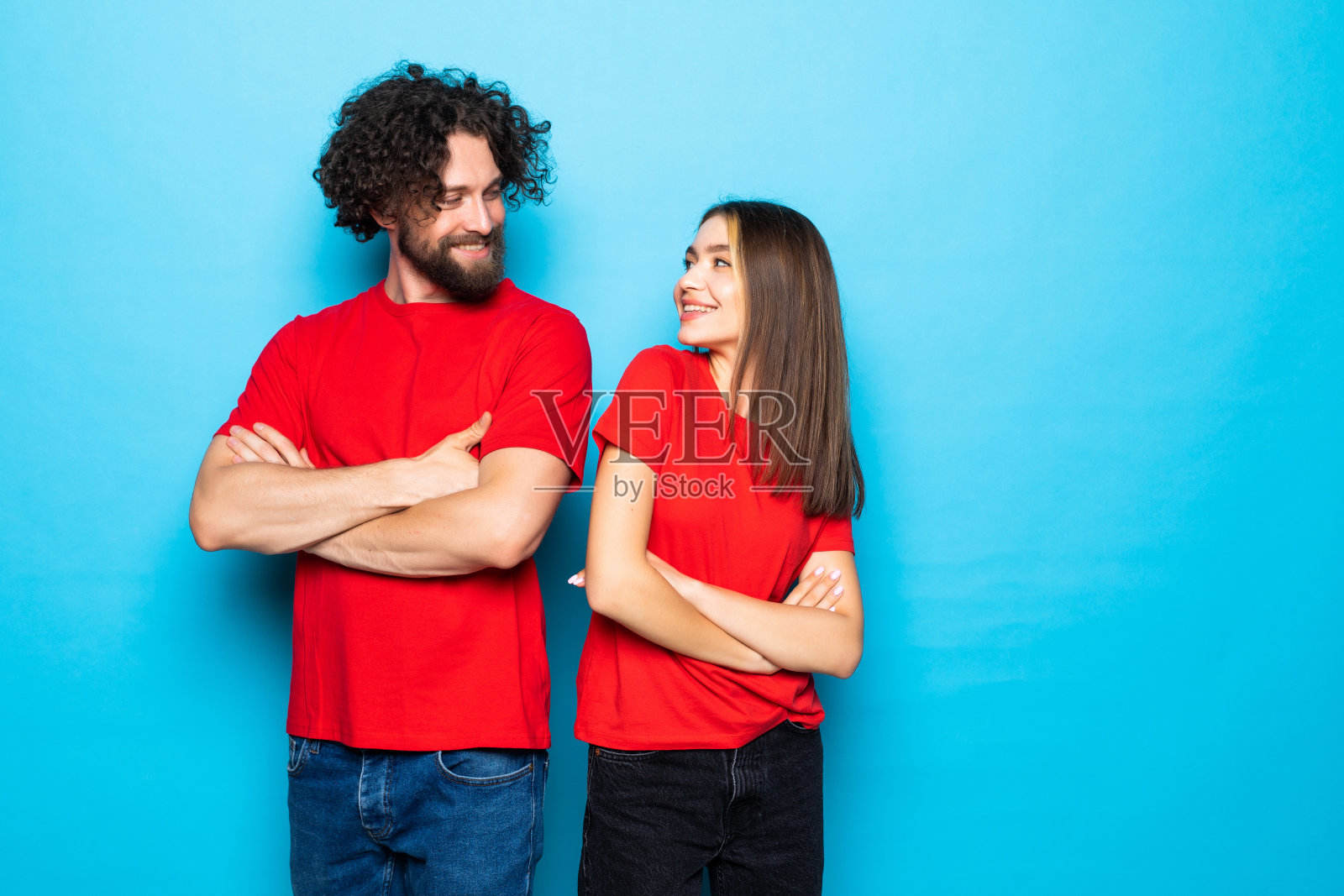 夫妇的肖像双臂交叉,不微笑穿着休闲红色t恤孤立的蓝色背景照片摄影图片