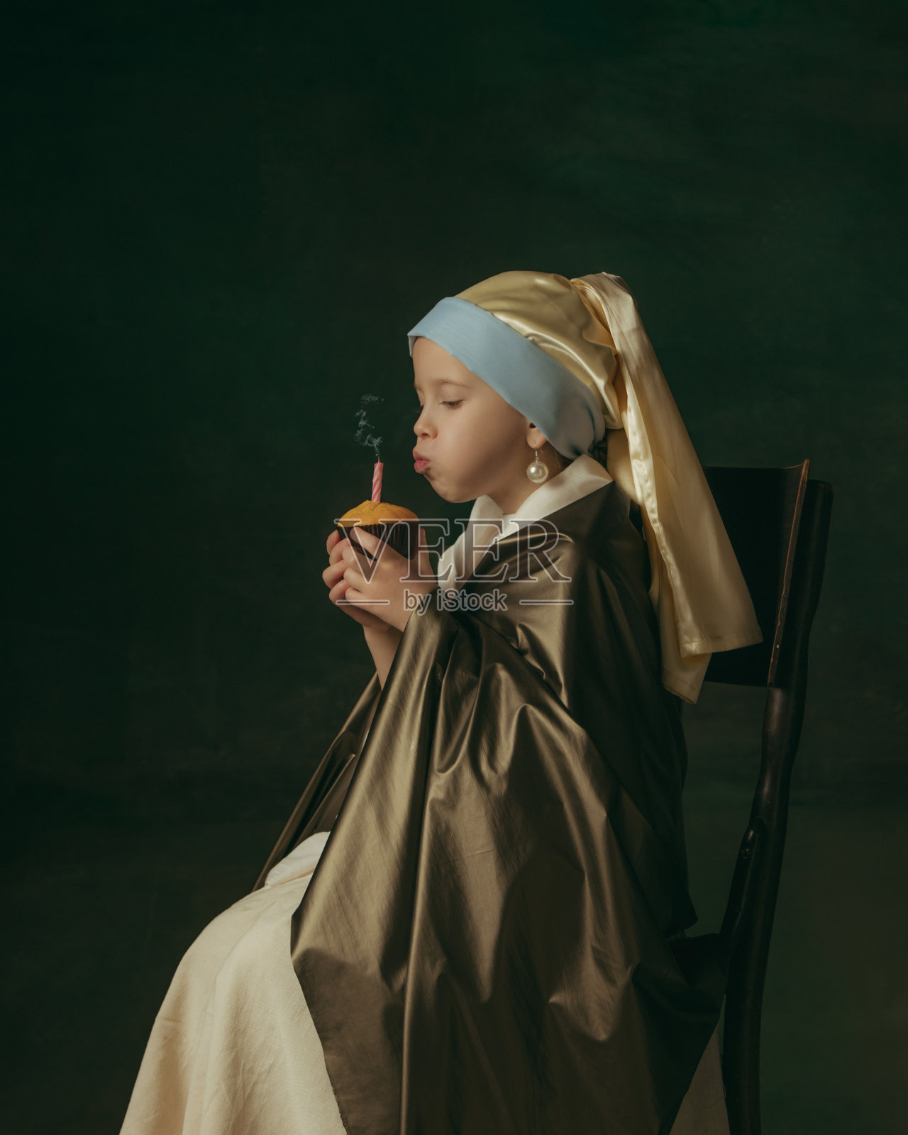 中世纪的小女孩,戴着珍珠耳环,背景是黑暗的画室。比较时代的概念,童年。时尚的创意设计,艺术视野,艺术品的新面貌。照片摄影图片