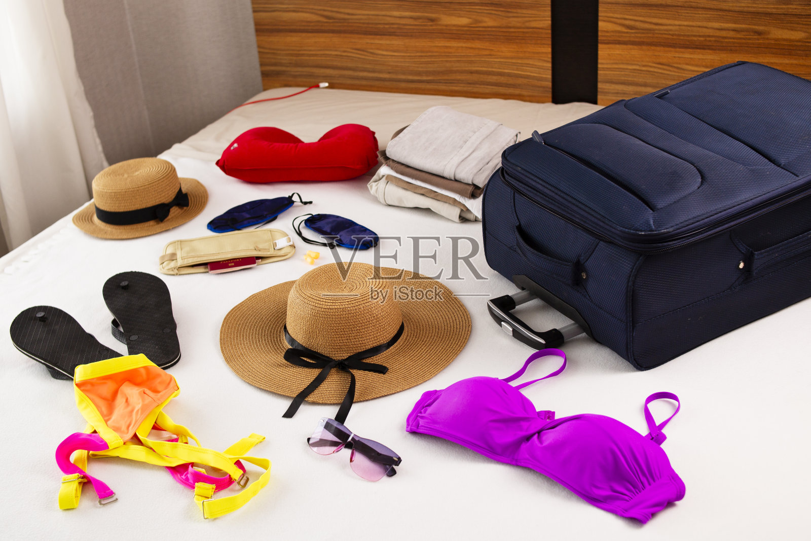 准备度假时,床上有旅行用品、饰品、衣服、文件和行李。照片摄影图片