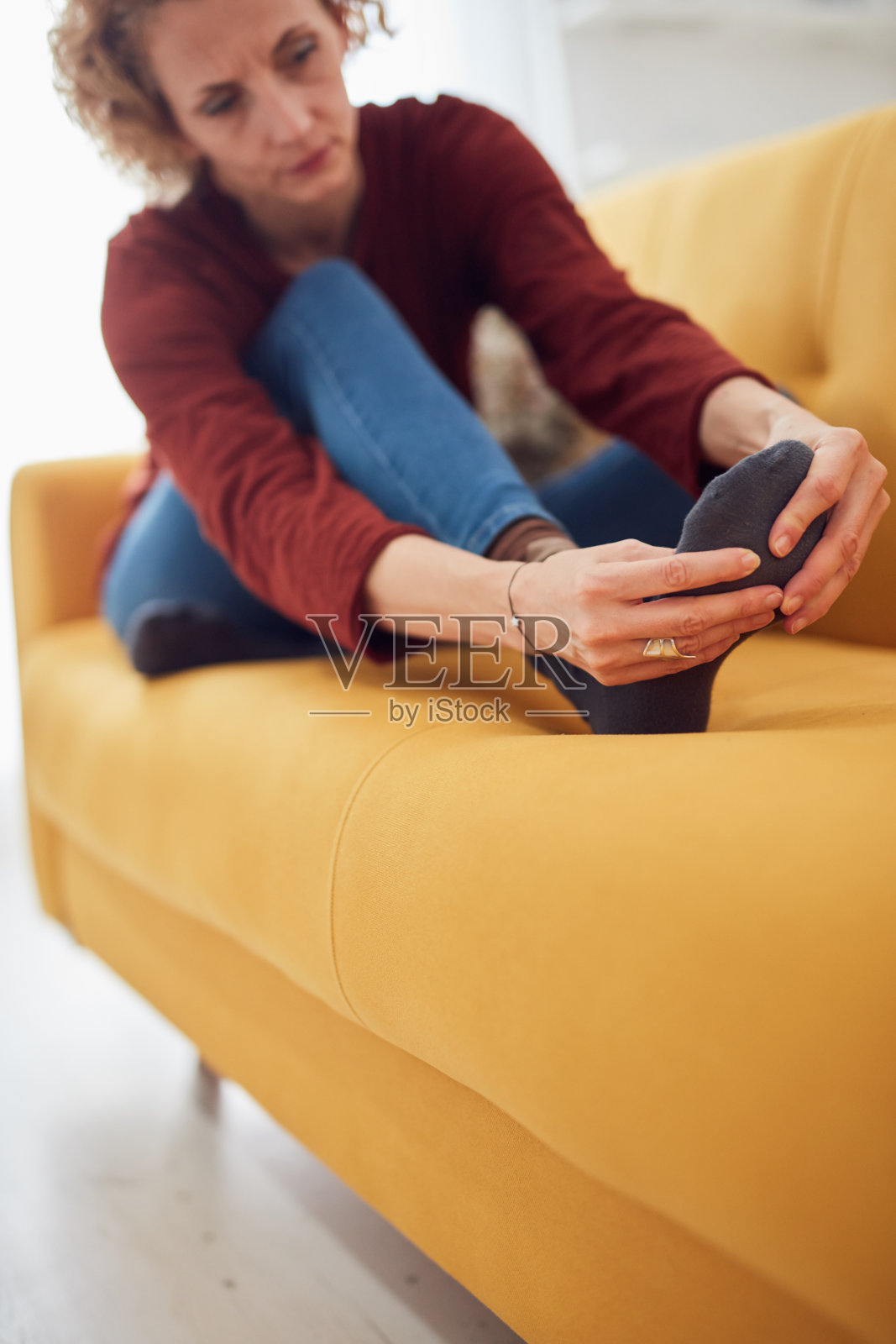 在家坐在沙发上,脚部剧痛的女人照片摄影图片