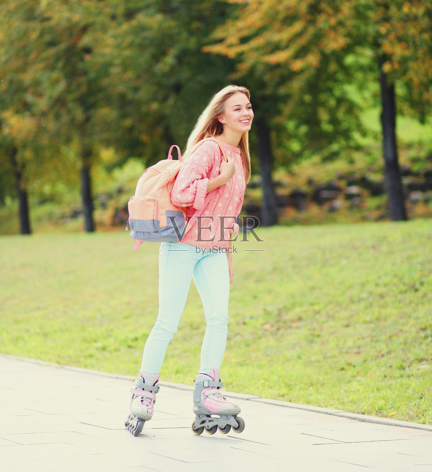 快乐的年轻微笑的女人在城市公园骑旱冰鞋照片摄影图片