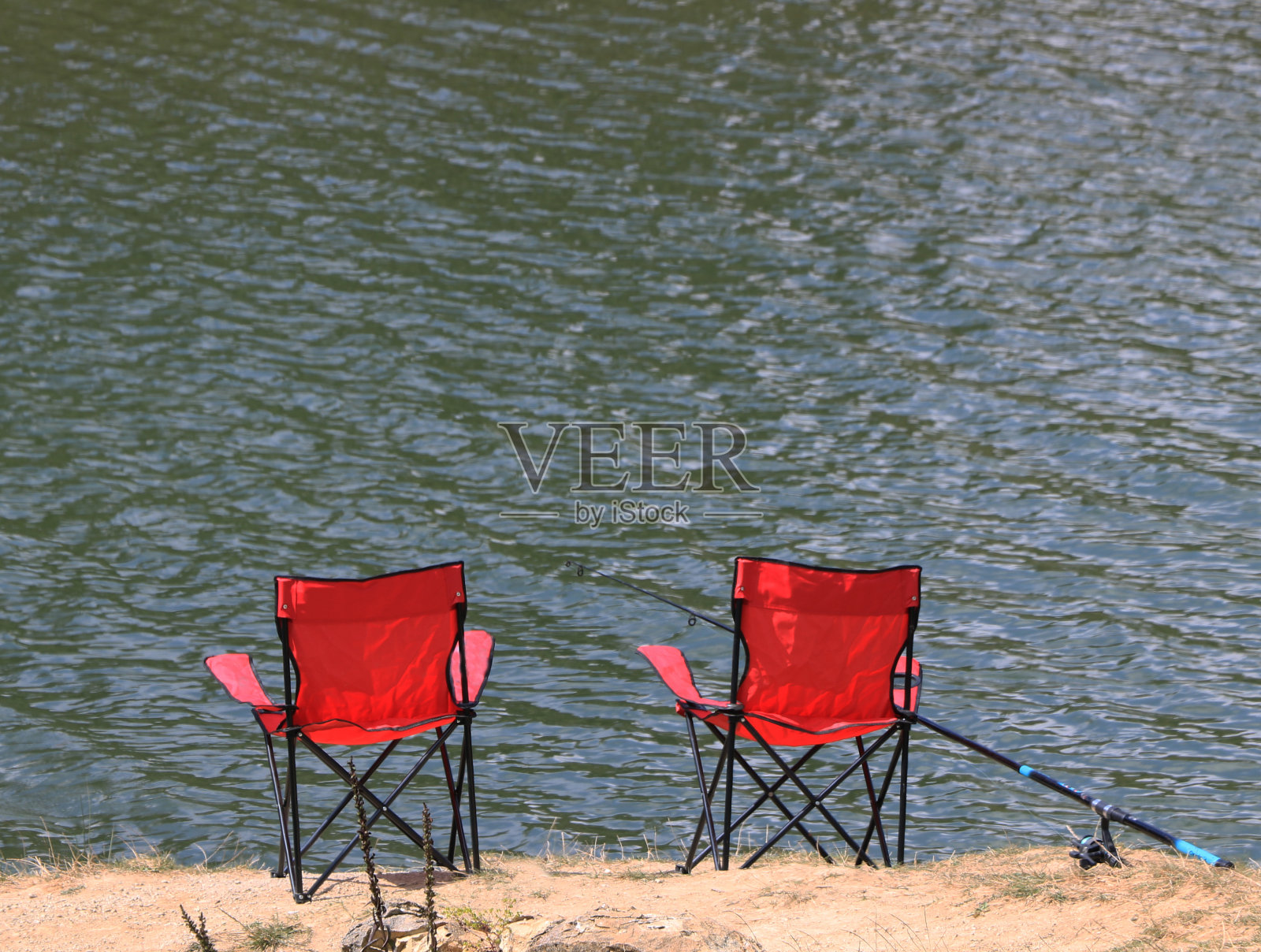 湖边的红色折叠椅和钓鱼线照片摄影图片