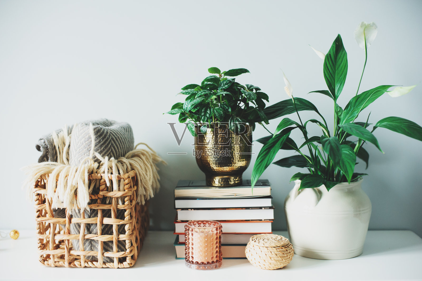 舒适的现代室内细节在斯堪的纳维亚风格室内植物,温暖的毯子,蜡烛和书照片摄影图片