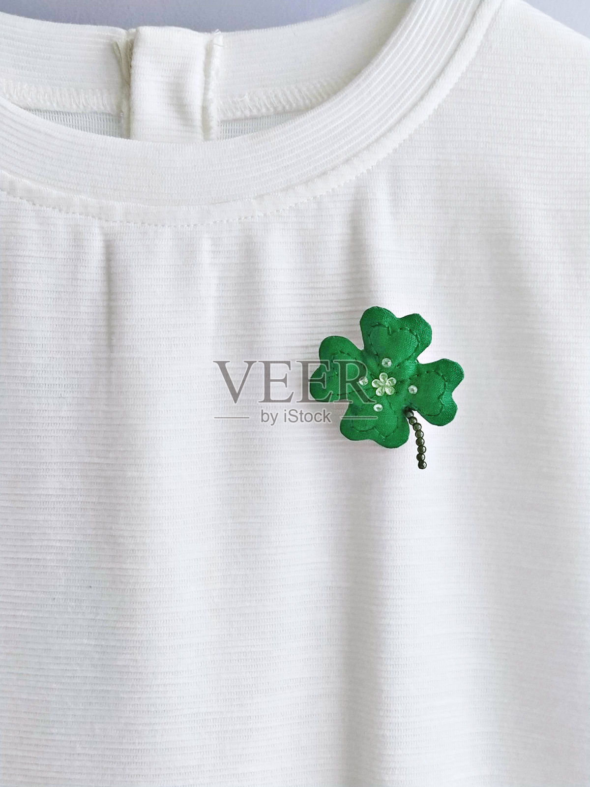 白色t恤上手工制作的三叶草胸针。庆祝圣帕特里克节照片摄影图片
