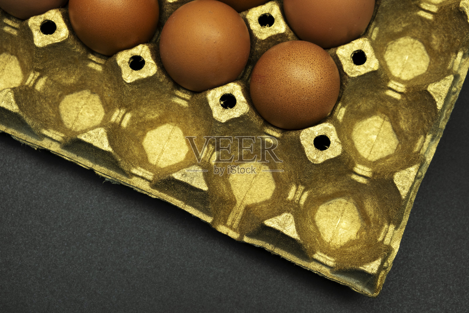 棕色的鸡蛋装在黑色背景的金色纸盒里照片摄影图片