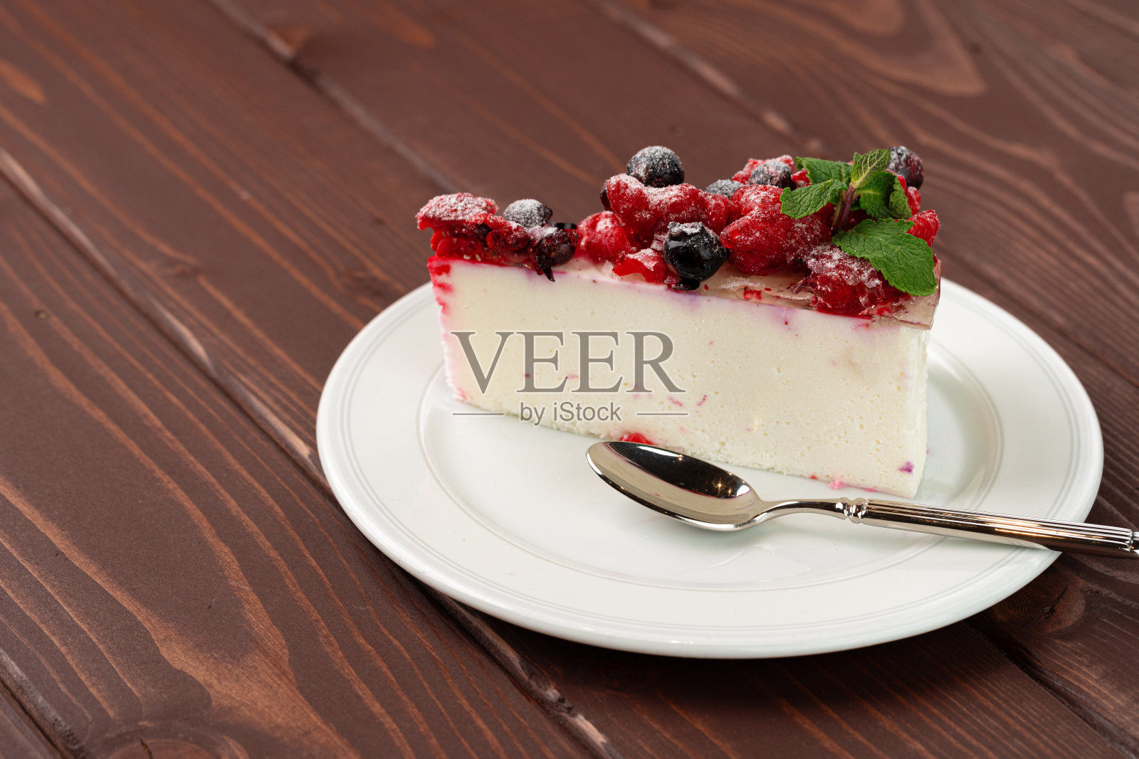 棕色的木桌上放着一块浆果芝士蛋糕照片摄影图片