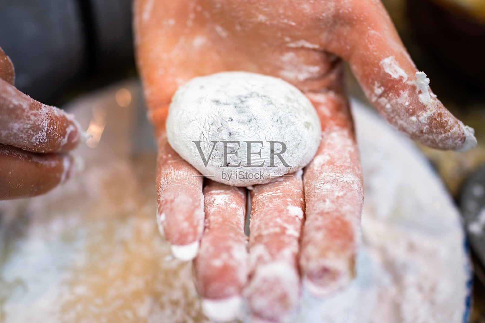 侧面宏观特写的女人脏手握自制的圆糯米黏日本年糕甜点在家里厨房由盘子照片摄影图片