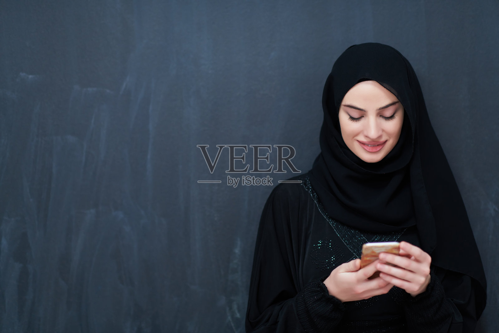 穿着传统服装或长袍的年轻穆斯林女商人使用智能手机照片摄影图片