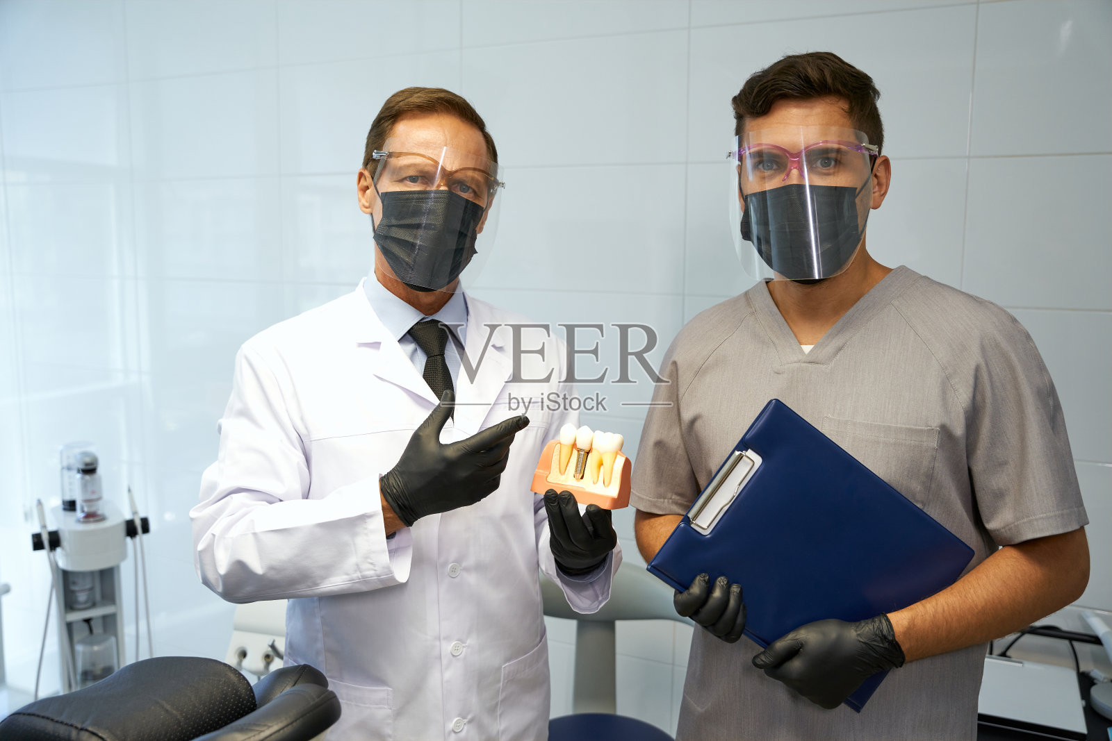 牙医穿着个人防护装备在工作场所摆姿势照片摄影图片