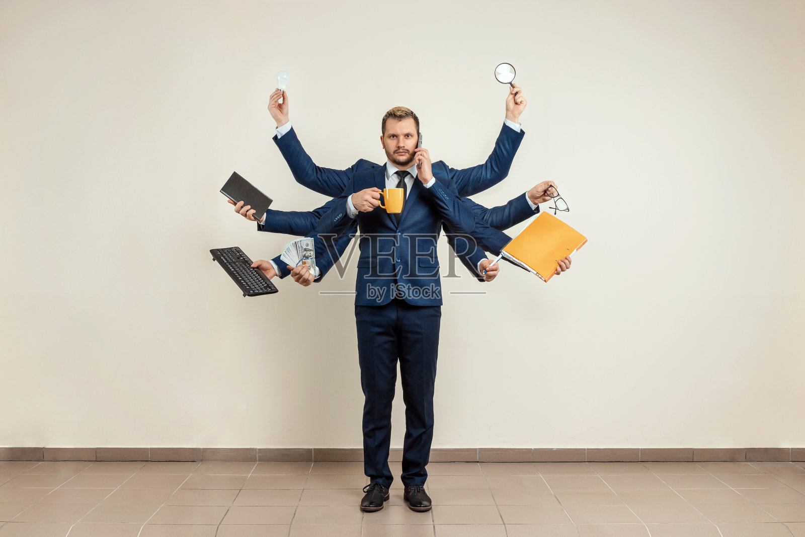 西装革履的商人。可以同时使用几样东西,杯子,放大镜,纸张,合同,电话。多任务处理,高效商务工作者的概念。照片摄影图片