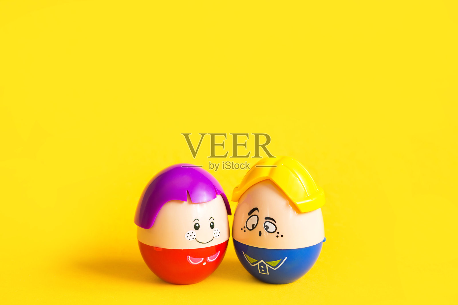 两个有趣的彩蛋男孩和女孩的脸在黄色的背景-复活节,春天。儿童玩具——一对男女、爱情、家庭的象征。本空间照片摄影图片