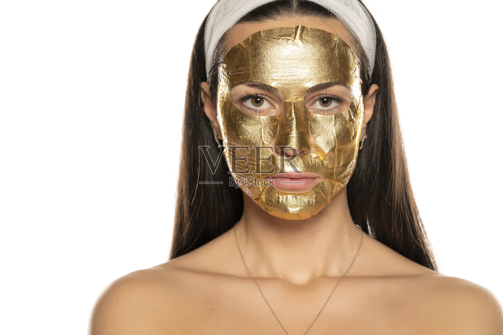 年轻女子摆姿势,脸上戴着金色面具照片摄影图片