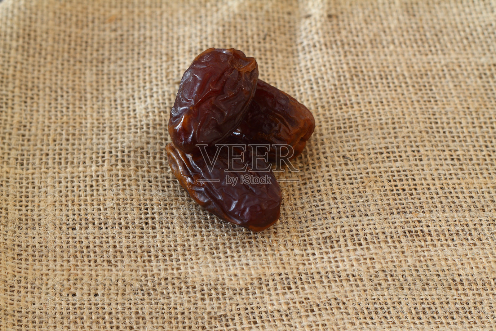 以麻袋为背景的约会干果。干枣一堆一堆地躺着照片摄影图片