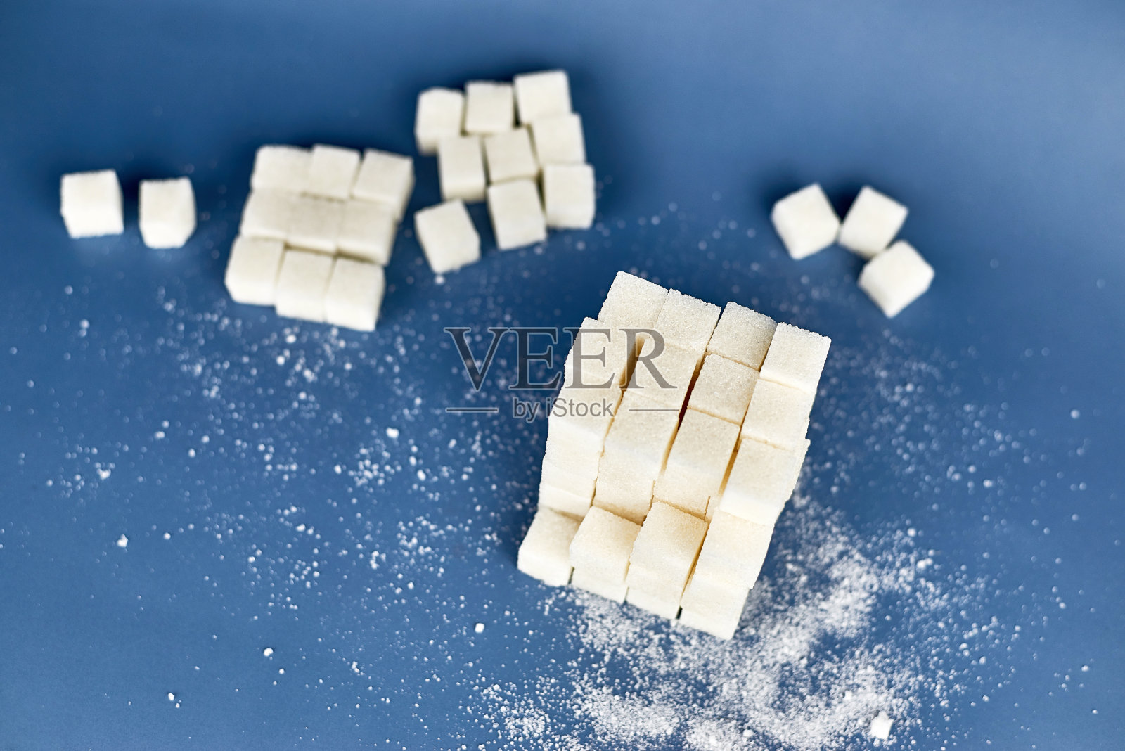 蓝色背景上的白糖块。照片摄影图片