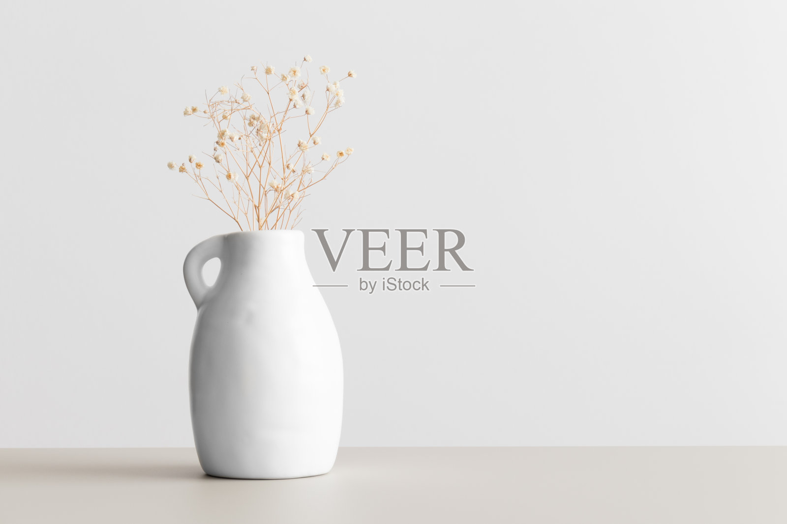 米色桌子上的花瓶里放着干燥的gypsophila。平铺与空白拷贝空间。照片摄影图片